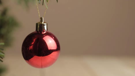 Christmas-red-bauble-hanging-from-tree-on-simple-background