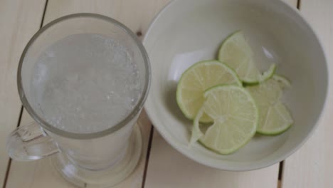 Pouring-glass-of-fresh-fizzy-water-lime-slices