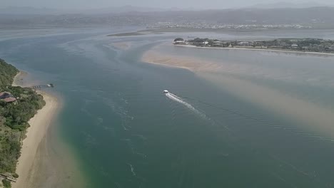 Tour-boat-stays-in-deep-channel-returning-to-port-in-Knysna,-aerial