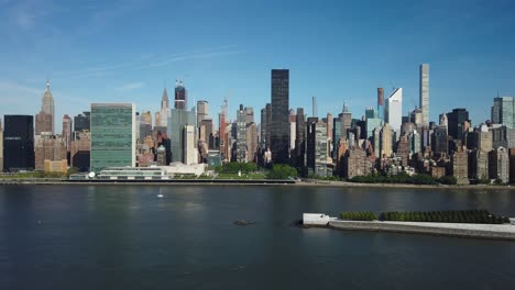 Establishing-shot-of-East-Side-Manhattan,-New-York-City-on-a-sunny-morning-with-East-River-and-Roosevelt-Island-in-the-foreground,-filmed-from-Long-Island-City
