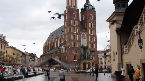 Krakow-church-old-town-square-birds-flying-towards-camera-in-slow-motion-above-tourists