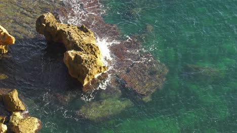 Tropical-ocean-waves-break-on-small-rocky-islets,-slow-motion-from-above
