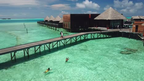 Luftaufnahme,-Drohnenaufnahme,-Um-Menschen-Herum,-Die-Im-Wasser-Spielen,-In-Villen-Am-Meer,-An-Einem-Sonnigen-Tag,-Auf-Der-Insel-Conrad-Rangali-Auf-Den-Malediven