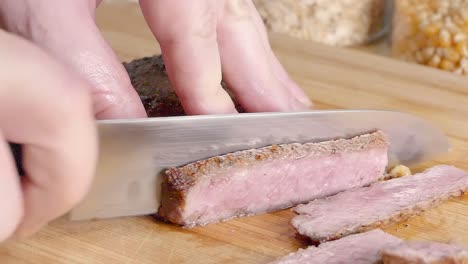 Close-Slow-Motion-Slider-Shot-of-Slicing-a-New-York-Strip-Steak-on-a-Wooden-Cutting-Board