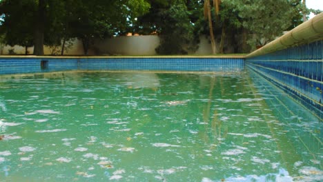 Ein-Schmutziger-Pool-Mit-Leuchtend-Blauen-Fliesen,-Gefüllt-Mit-Weißem-Schockpulver,-Das-Auf-Der-Oberfläche-Schwimmt-–-Totale
