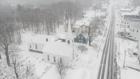 Blizzard-snowfall-over-church-small-town-aerial