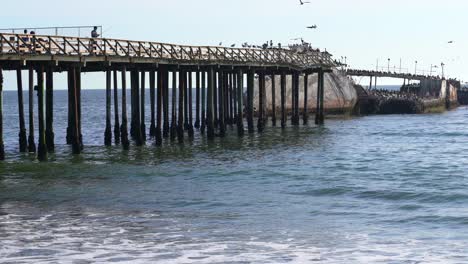 Man-fishing-on-the-pier-of-Seacliff-State-Beach-in-Aptos,-California