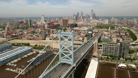 Aerial-rotating-view-of-Philadelphia-Ben-Franklin-Bridge-and-skyline-in-the-summer-with-cars-and-traffic-driving-on-the-road