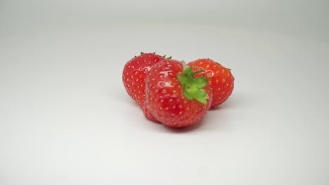 Three-Delicious-and-Fresh-Strawberries-On-The-Rotating-Table-With-Pure-White-Background---Close-Up-Shot
