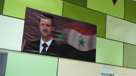 Eine-Rack-Fokus-Aufnahme,-Ein-Bild-Des-Syrischen-Präsidenten-Baschar-Al-Assad,-Angezeigt-Auf-Einem-Anderen-Farbschema-Eines-Grünen-Fliesenhintergrunds