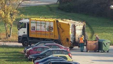 Dumpster-MAN-truck-with-two-workers-emptying-the-full-trash-bins