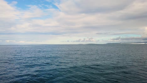 4K-Hawaii-Kauai-Bootfahren-Auf-Dem-Meer,-Das-Von-Rechts-Nach-Links-Schwimmt-Und-In-Der-Ferne-Die-Brandung-Und-Die-Bewölkte-Küste-Sichtbar-Macht