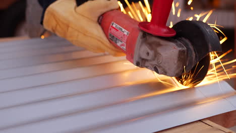 A-construction-worker-using-a-power-tool-angle-grinder-to-cut-metal-and-send-glowing-bright-sparks-flying-in-slow-motion