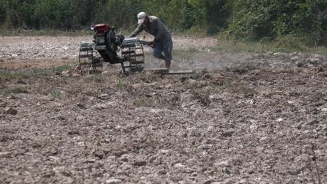Exterior-Wide-Static-Shot-of-a-Man-Ploughing-the-Field-in-the-Sunny-Hot-Day