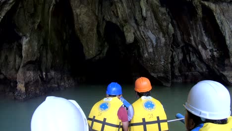 People-with-lifejackets-and-helmets-swim-on-a-boat-into-a-cave-with-magnificent-stalactites