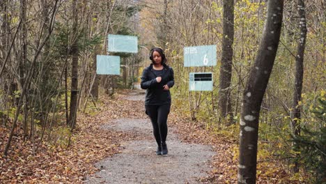 Sporty-woman-starts-jogging-through-the-autumnal-forest---digital-generated-tracking-holograms-for-steps,-music-and-pulse-monitoring