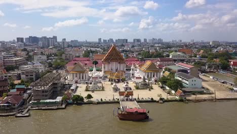 Buddhist-temple-on-the-banks-of-Chao-Phraya-river-in-Bangkok,-aerial-view