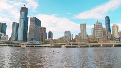 a-group-of-people-kayaking-in-brisbane-cbd-river-near-southbank-parkland-with-brisbane-city-background