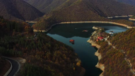 Flug-über-Den-Vucha-Staudamm-Während-Eines-Farbenfrohen-Herbstes-Mit-Fahrendem-Boot-Im-Wasser
