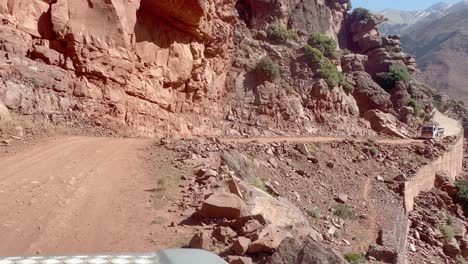 Pulling-to-the-side-of-a-precarious,-narrow-mountain-road-on-a-cliff-so-a-truck-can-pass-in-the-High-Atlas-Mountains-of-Morocco