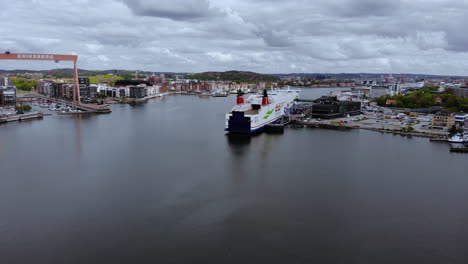 Un-Barco-Enorme-Y-Una-Grúa-Pórtico-En-El-Puerto-Industrial-De-Gotemburgo,-Suecia,-En-Un-Día-Nublado:-Disparo-De-Drones-Ascendente-Lento