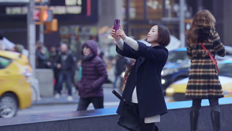 An-Asian-woman-posing-for-a-selfie-in-Times-Square,-New-York-City