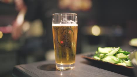 Vaso-De-Burbujeante-Cerveza-Japonesa-En-La-Mesa-De-Madera-Dentro-Del-Restaurante-En-Kyoto,-Japón