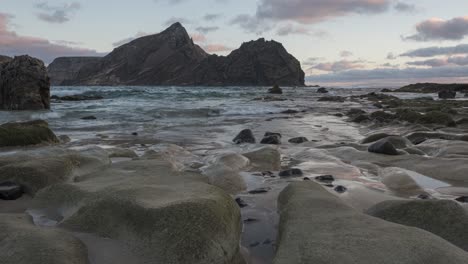 Low-angle-time-lapse-shot-scenic-beach-at-sunset-light,-Rocks-in-foreground