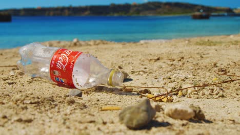An-Empty-Plastic-Coca-Cola-Bottle-On-The-Beach-In-Curacao---closeup-shot
