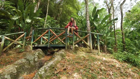 stylish-girl-in-red-jacket-sitting-in-a-wooden-bridge-on-a-park