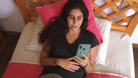 Mujer-Joven-Riendo-Haciendo-Video-Chat-Usando-El-Teléfono-Móvil-En-La-Cama