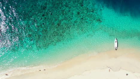 Kristallklares-Smaragdgrünes-Wasser-Der-Ruhigen-Türkisfarbenen-Lagune,-Das-Sonnenlicht-Reflektiert,-Verankerte-Boote-Am-Weißen-Sandstrand-In-Bali