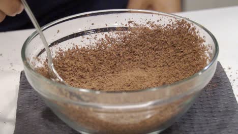 Slow-motion-close-up-of-a-girl-moving-grated-chocolate-flecks-around-in-a-bowl