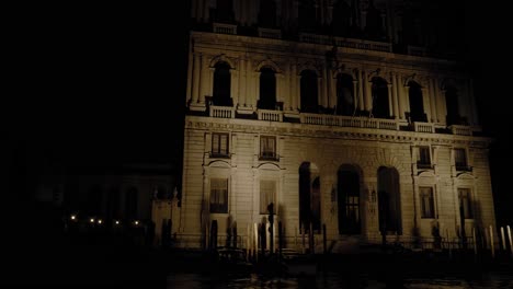 Illuminated-facade-of-the-Palazzo-Corner-della-Ca'-Granda,-night-boat-tour-along-the-Grand-Canal-in-Venice,-Italy