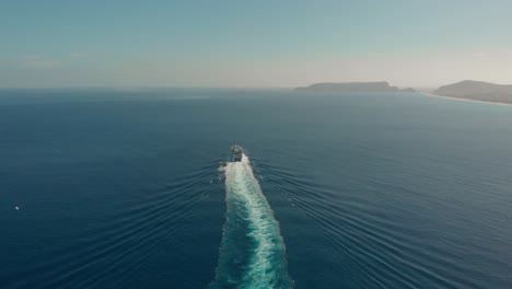 Aerial-high-view-Passenger-vessel-moving-away,-island-as-Background