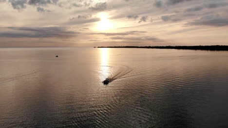 Aerial-footage-of-a-boat-cruising-in-a-beautiful-bay-at-sunset-during-summer-in-Caseville,-Michigan,-USA