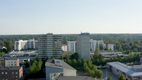 Reversing-aerial-shot-of-two-large-towers-and-a-round-building-below,-Finland