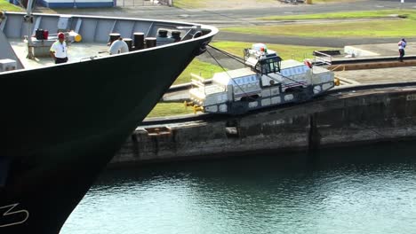 Bow-of-the-ship-and-locomotive-slowly-pulling-it-thru-the-Gatun-locks,-Panama-canal