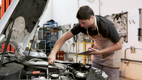 Hispanic-male-car-mechanic-holding-clipboard-reinserts-dipstick