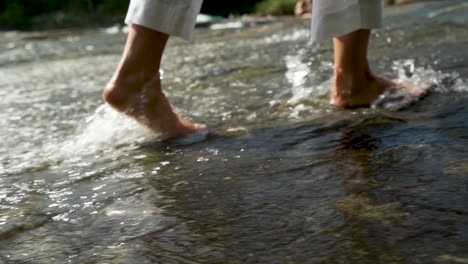 Slow-motion-of-feet-walking-through-the-water-in-a-river