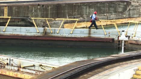 Man-walking-on-the-closed-gates-of-the-chamber-at-Gatun-locks,-Panama-canal