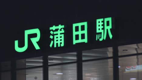 Señal-Verde-De-Neón-De-La-Estación-Kamata-Jr-Que-Se-Ilumina-Por-La-Noche-En-La-Ciudad-De-Ota,-Tokio,-Japón