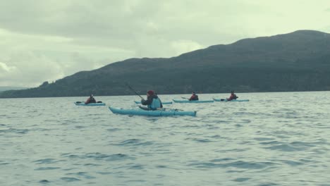 Kayak-group-paddling-on-lake-in-front-of-mountains