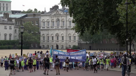 Hundreds-of-National-Health-Service-staff-and-key-workers-march-with-a-large-blue-banner-that-says,-â€œEnd-NHS-Pay-Inequality