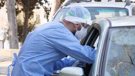 A-medical-worker-performs-a-drive-through-Coronavirus-swab-test-on-a-person-in-their-car-in-Pafos-City,-Cyprus-Greece-during-the-COVID-19-pandemic