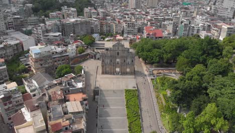 Reversing-tilt-reveal-aerial-view-of-Ruins-of-Saint-Paul's,-Macau-and-surrounding-area