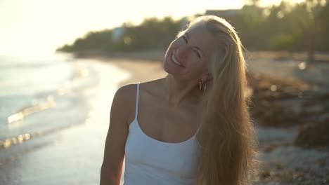 Slow-motion-of-mature-woman-backlit-on-beach-swinging-her-hair-around-from-side-to-side-eventually-looking-and-smiling-at-camera
