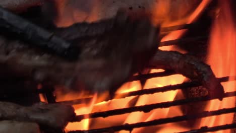 The-cooking-of-some-pork-on-a-BBQ-close-up-with-flames-in-Ireland-and-a-hot-day