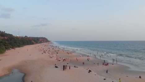Rotating-aerial-view-showing-large-number-of-tourists-enjoying-their-holiday-on-Varkala-beach-during-day