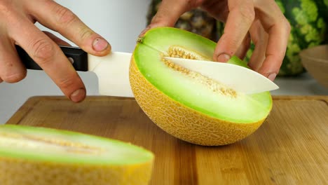 Schneiden-Sie-Melone-Auf-Einem-Bambusschneidebrett-Mit-Einem-Keramikmesser